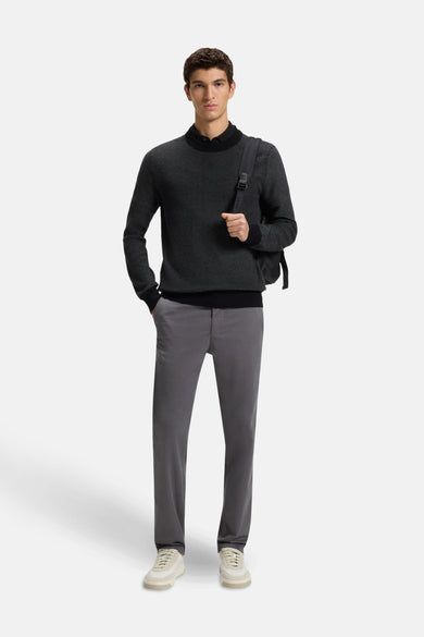 Zwarte rondehals trui van BOSS ORANGE gedragen met een grijze broek en een rugzak.
