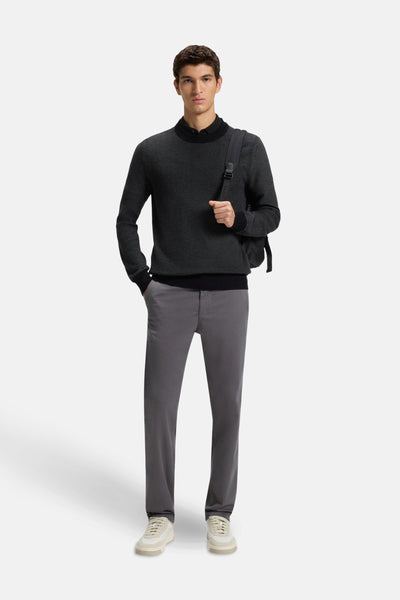 Zwarte rondehals trui van BOSS ORANGE gedragen met een grijze broek en een rugzak.