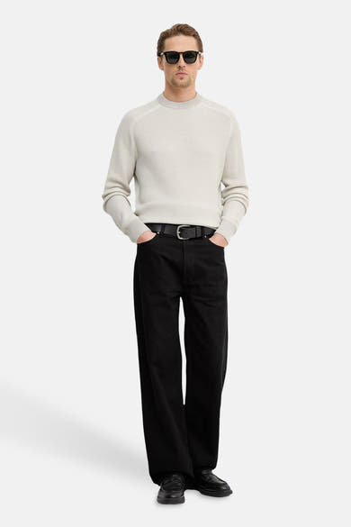 Pull col rond gris de BOSS ORANGE, porté avec un pantalon noir, des chaussures en cuir et des lunettes de soleil.