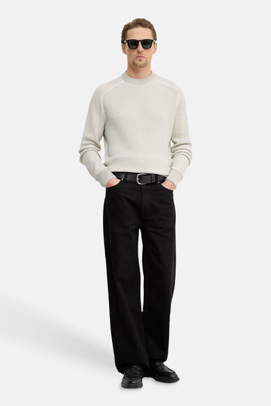 Pull col rond gris de BOSS ORANGE, porté avec un pantalon noir, des chaussures en cuir et des lunettes de soleil.