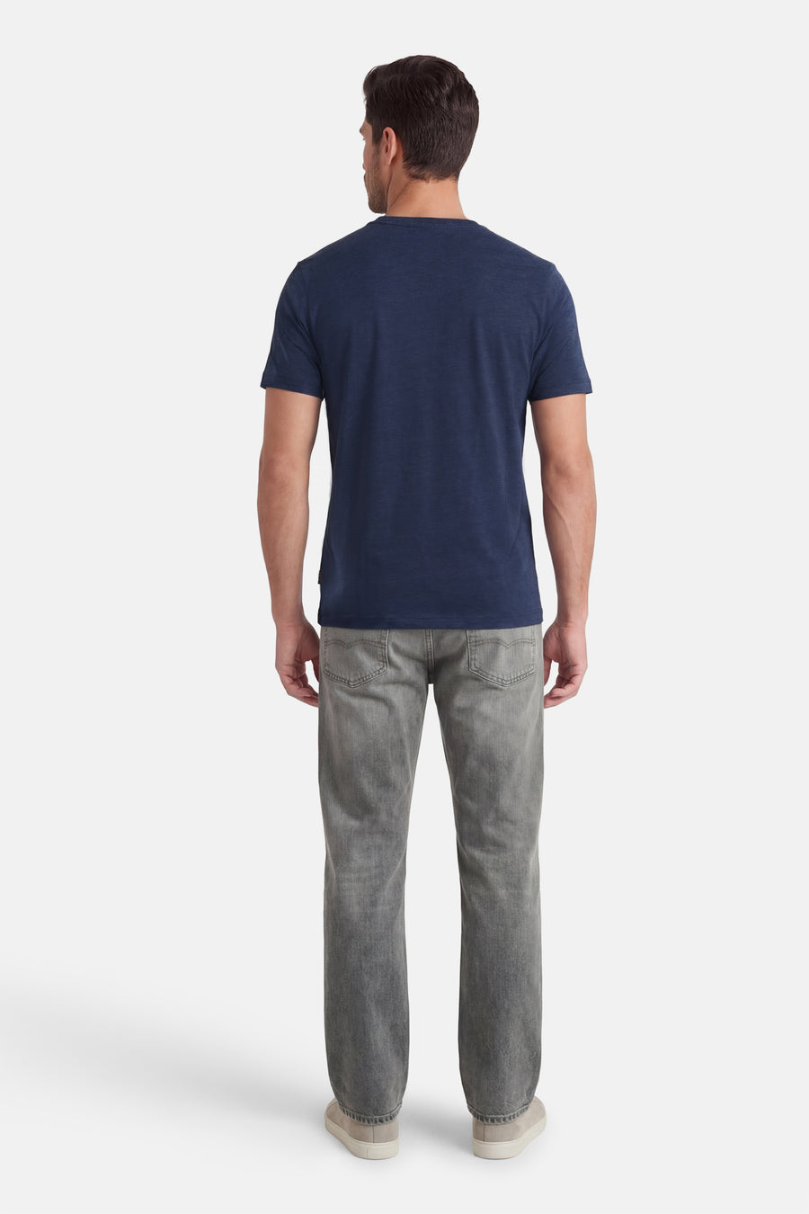 T-shirt à manches courtes bleu de BOSS ORANGE, vu de dos, porté avec un jean gris et des chaussures de sport beiges.