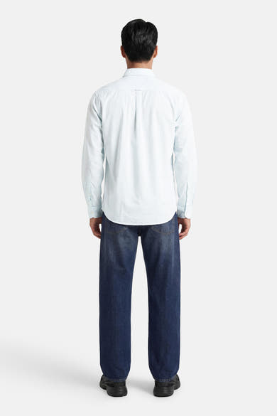Chemise turquoise à manches longues de BOSS ORANGE, portée de dos avec un jean bleu foncé et des baskets noires.