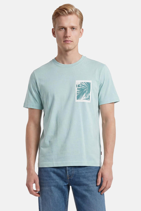 T-shirt turquoise de BOSS ORANGE avec motif rectangulaire de feuilles de palmier et 7.8 sur la poitrine, porté par un homme.