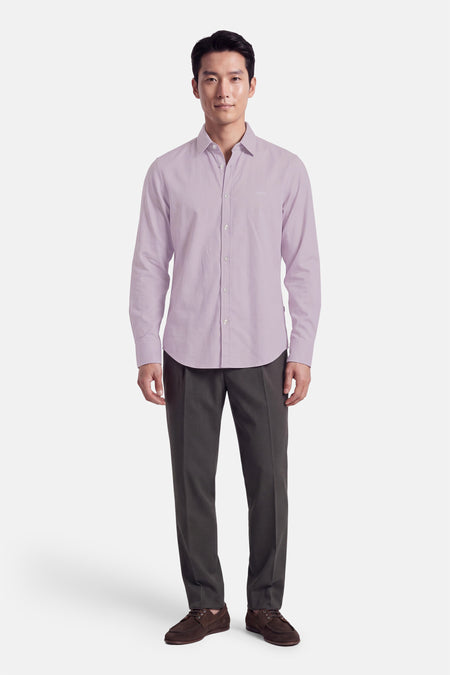 Chemise à manches longues violette par BOSS ORANGE, boutonnée, coupe ajustée, portée avec pantalon gris et chaussures marron, vue de face.