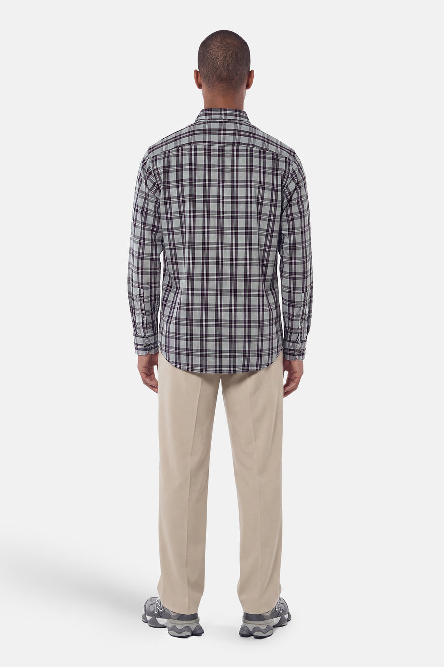 Grey plaid long-sleeve shirt back view, featuring dark grid pattern and buttoned cuffs, worn with beige trousers and grey sneakers.