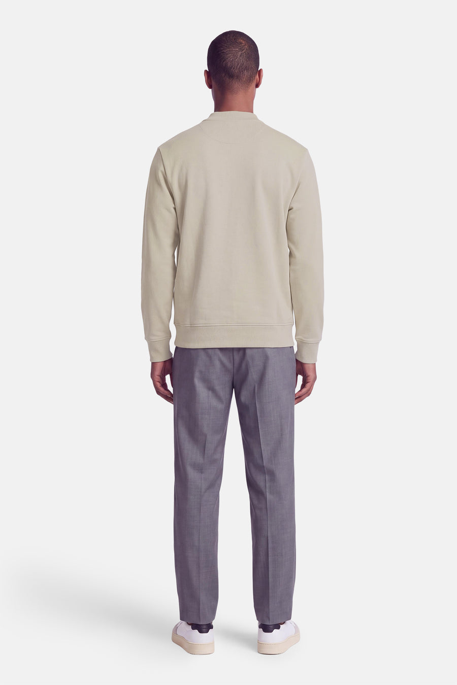 Sweat à col roulant beige de BOSS ORANGE, vue arrière, coupe ajustée, manches longues, bordures côtelées, porté avec pantalon gris et baskets blanches.