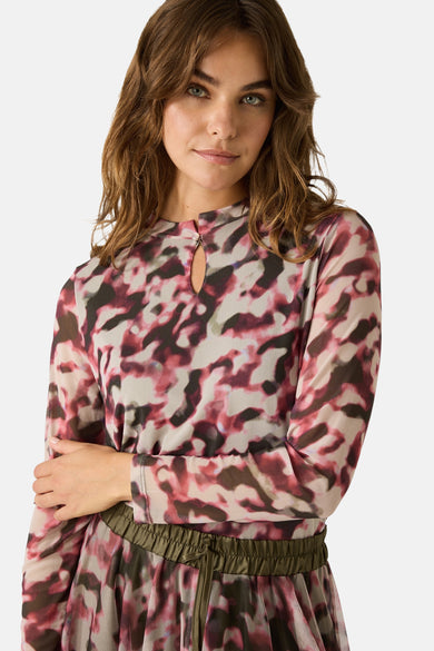 Multikleuren T-shirt met lange mouwen van MORE & MORE, gedragen met een gevlekte jurk en groene enkellaarsjes.
