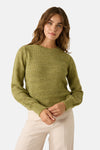 Groene trui met ronde hals van MORE & MORE, gedragen met een crèmekleurig jasje en een crèmekleurige broek, en een roze en beige geruite sjaal.