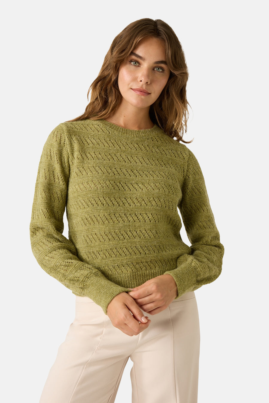 Groene trui met ronde hals van MORE & MORE, gedragen met een crèmekleurig jasje en een crèmekleurige broek, en een roze en beige geruite sjaal.
