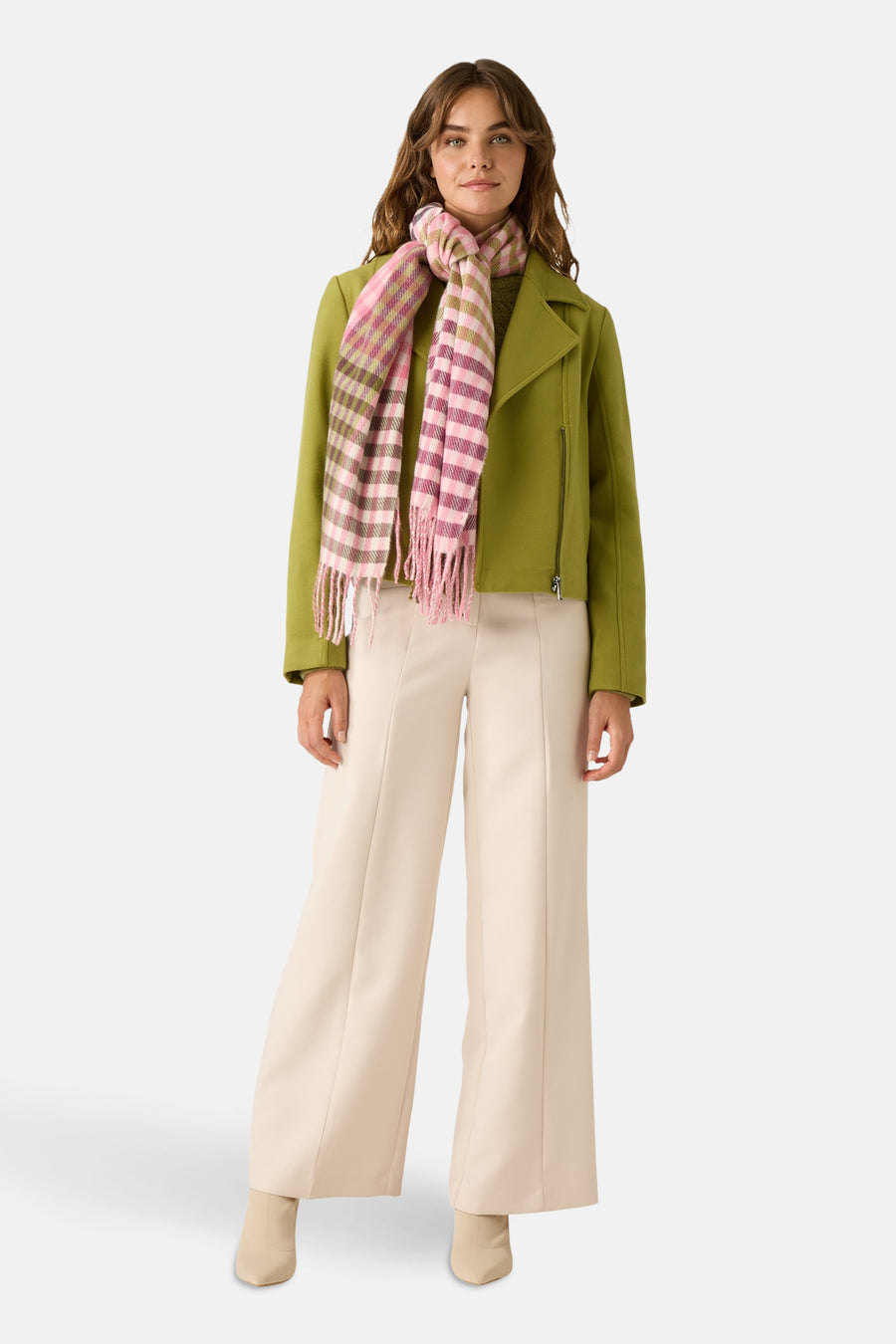 Pull vert à col rond de MORE & MORE, porté avec une veste et un pantalon de couleur crème, et une écharpe à carreaux rose et beige.