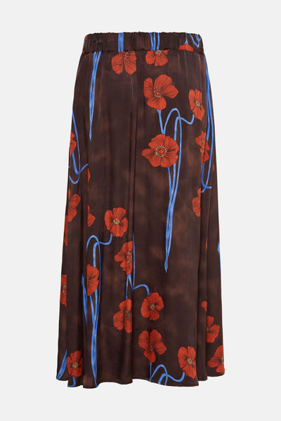 Lange meerkleurige rok van MORE & MORE met rood bloemenpatroon en blauwe stelen op een bruine achtergrond.