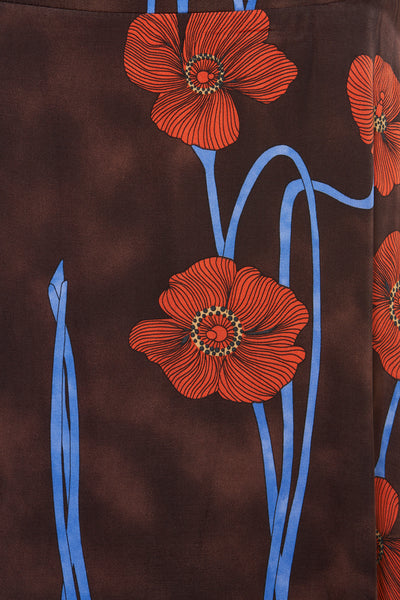 Multikleurige lange rok van MORE & MORE, met rood bloemenpatroon en blauwe stelen op een donkerbruine achtergrond.