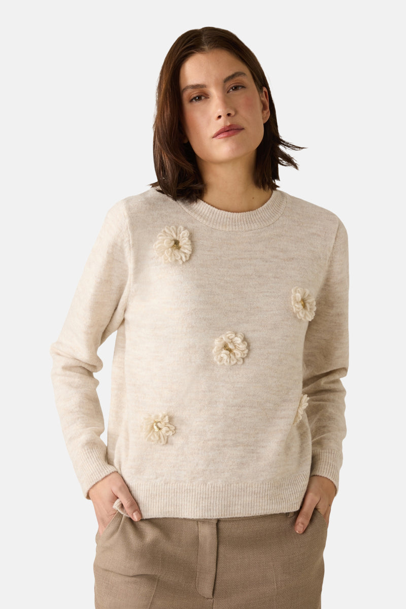 Beige ronde hals trui van MORE & MORE, versierd met decoratieve bloemen, gedragen met een bijpassende bruine broek, muts en sjaal.