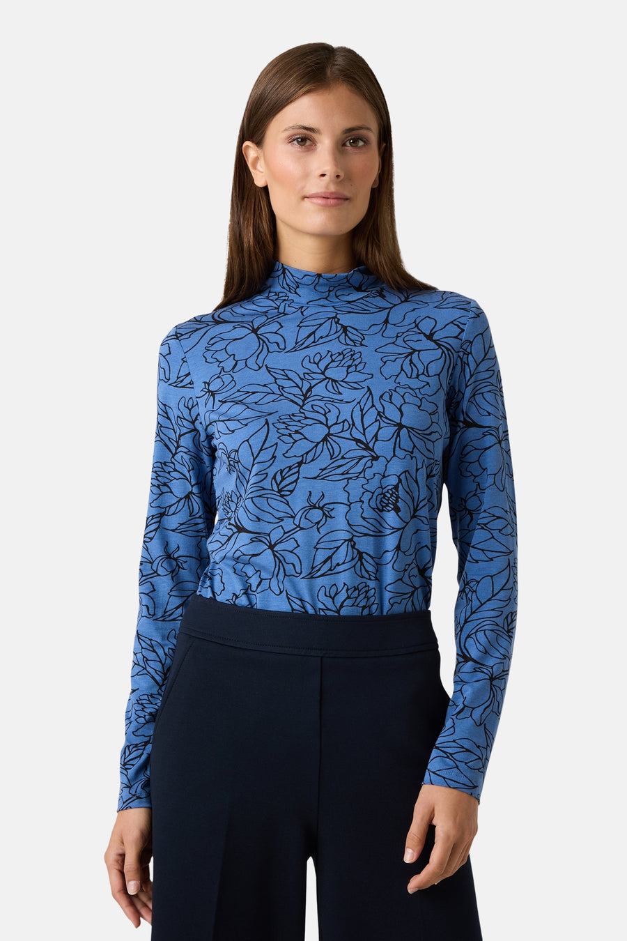 Blauwe T-shirt met lange mouwen, van MORE & MORE, met zwart bloemenpatroon, gedragen met een marineblauwe wijde broek en hakken.