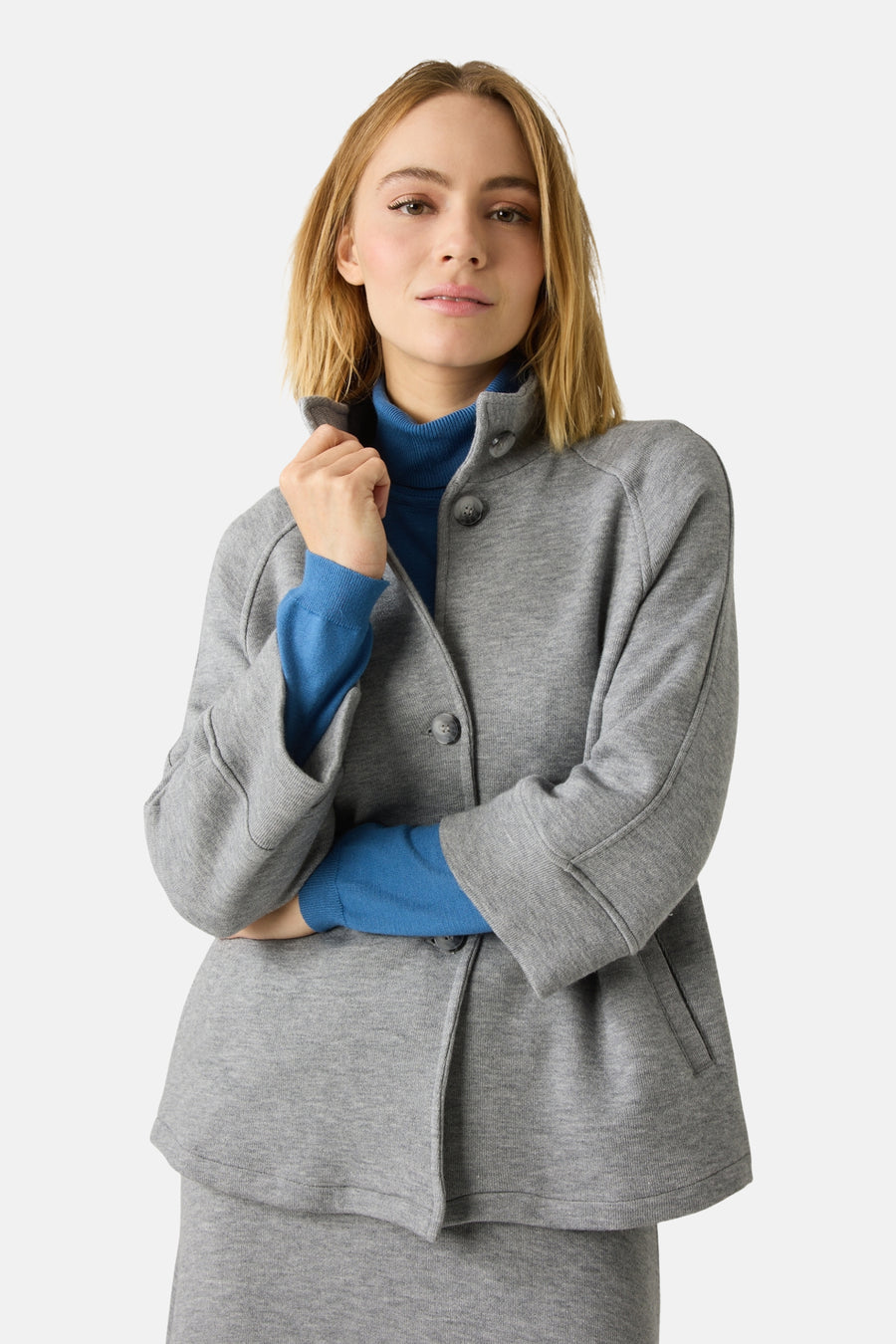 Grijze bodywarmer van MORE & MORE, gedragen met een blauwe coltrui en een bijpassende midirok.