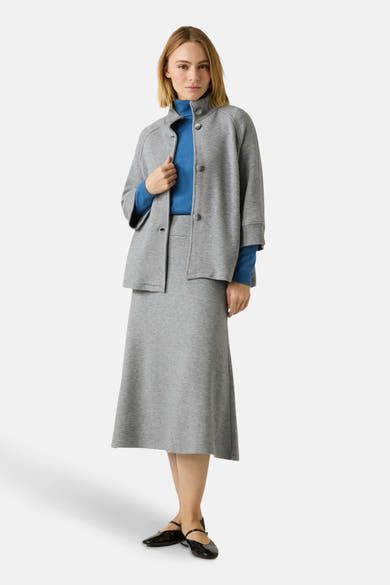 Gilet gris de MORE & MORE, porté avec un col roulé bleu et une jupe midi assortie.