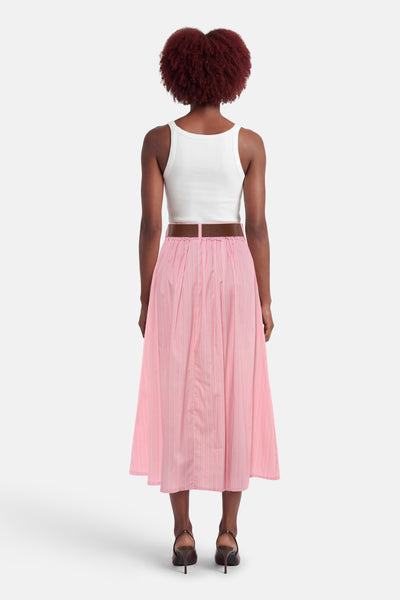Jupe rose à rayures verticales de Terra di Siena, portée avec une ceinture marron et un débardeur blanc.