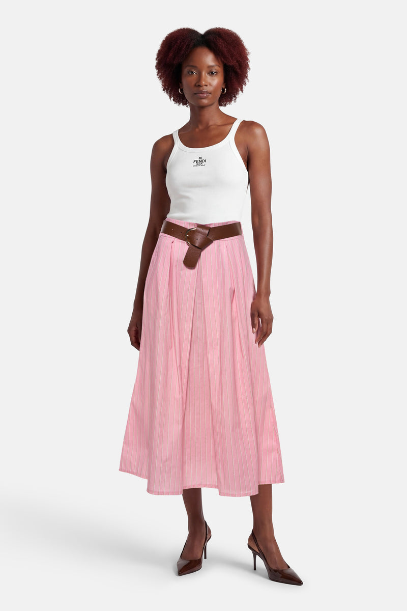 Jupe rose à rayures verticales de Terra di Siena, portée avec un débardeur blanc et une ceinture marron, chaussures à talons foncées.