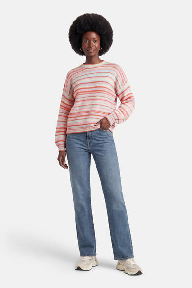 Multikleuren rondehals trui van Terra di Siena, met horizontale strepen, gedragen met een blauwe jeans en neutrale sneakers.