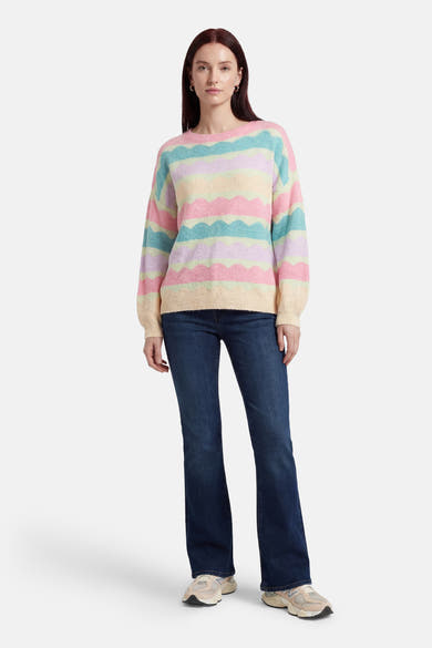 Multikleuren rondehals trui van Terra di Siena, met pastelkleurige golvende strepen, gedragen met een blauwe bootcut jeans.