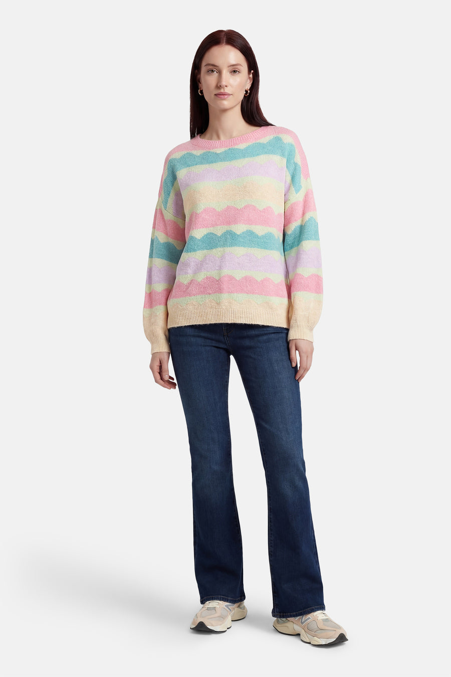 Multikleuren rondehals trui van Terra di Siena, met pastelkleurige golvende strepen, gedragen met een blauwe bootcut jeans.