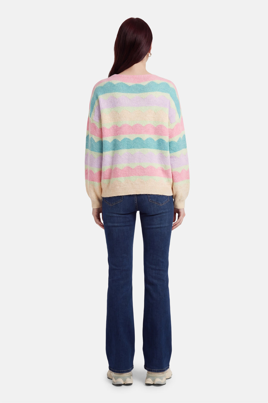 Multikleuren rondehals trui van Terra di Siena, met pastelkleurige golvende strepen, gedragen met een uitlopende jeans.