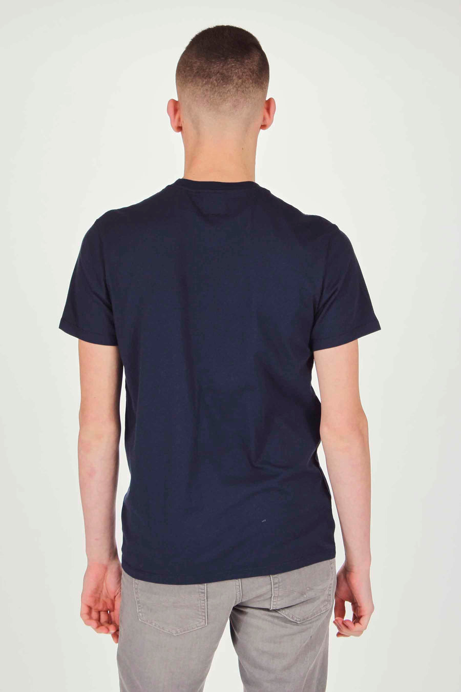 T-shirt bleu marine à manches courtes de Levi's, vu de dos, porté avec un pantalon gris.
