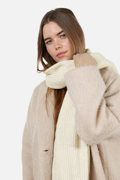 Écharpe écru de BARTS, portée avec un manteau beige et des gants assortis.