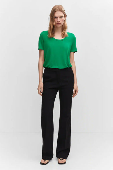 Green short-sleeve top with rounded neckline, worn with black wide-leg pants and flip-flops, front view.