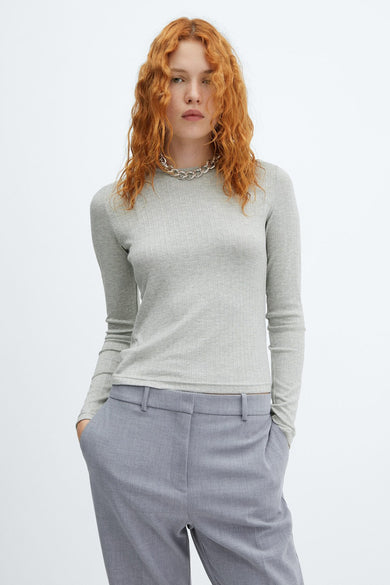 Top gris uni à manches longues de MANGO, porté avec un collier en argent et un pantalon tailleur assorti.