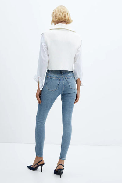 Light blue skinny jeans from back view, featuring classic five-pocket design and slim fit, worn with white ribbed top and navy heels.