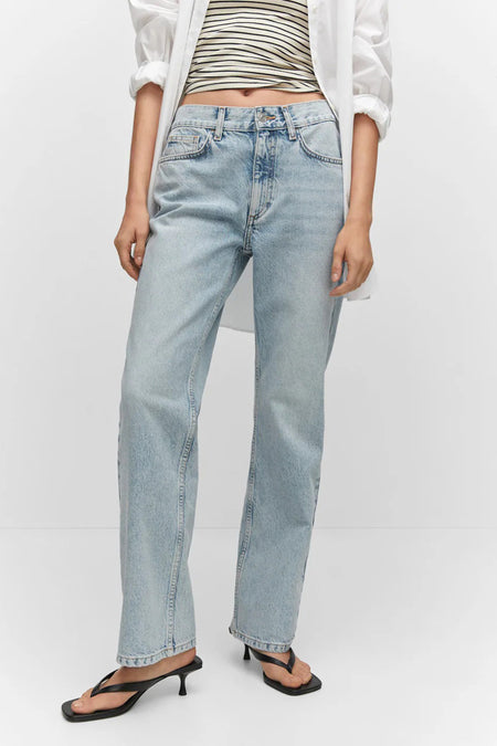 Rechte blauwe jeans van MANGO, gewassen met een hand in de zak, gedragen met een gestreept T-shirt en een wit overhemd.
