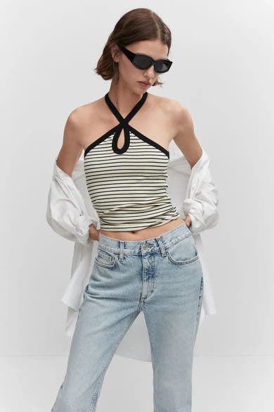Jean droit bleu de MANGO, délavé, porté avec un haut rayé et une chemise blanche.