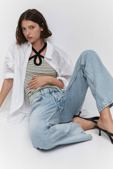 Jean droit bleu de MANGO, style décontracté, porté avec un top rayé et une chemise blanche.