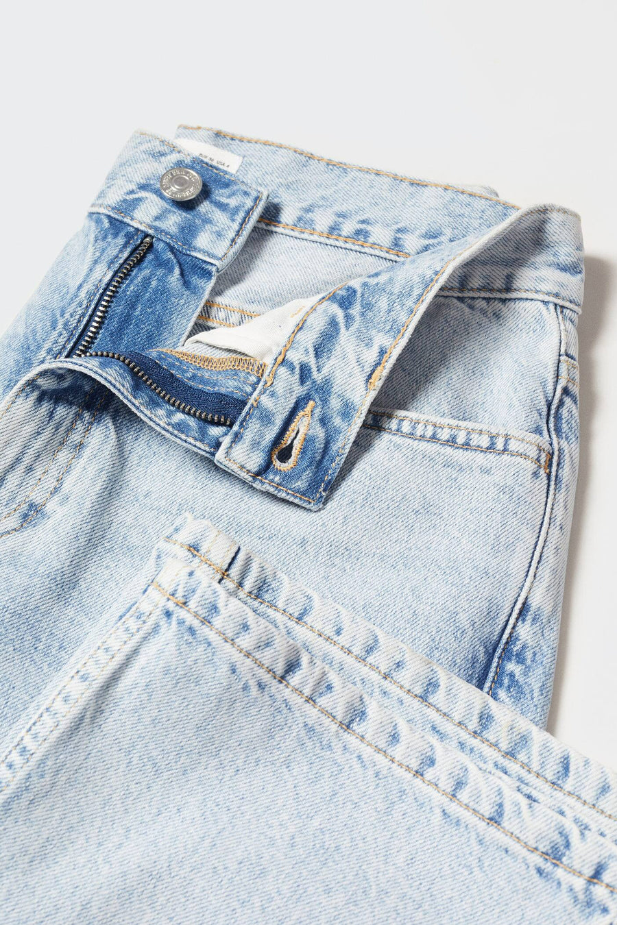 Jean droit bleu de MANGO, détail de la taille ouverte avec fermeture éclair et bouton apparent.