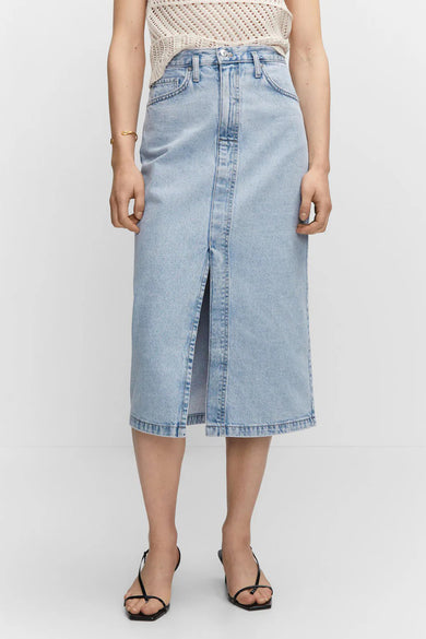 Light blue denim midi skirt with front slit and classic five-pocket design, worn with a white knit top and black sandals, front view.
