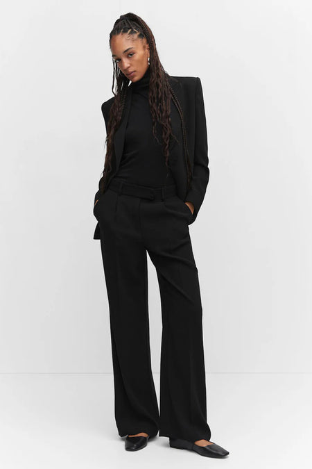 Black wide-leg suit trousers with structured fit and belt, worn with matching blazer and turtleneck, full-length front view