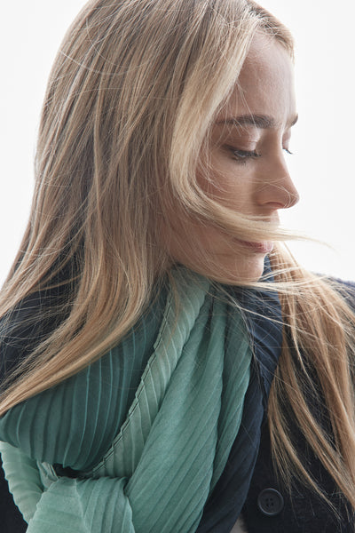 Foulard vert de STREET ONE, à plis, porté avec une veste foncée et des cheveux blonds tombant sur le visage.
