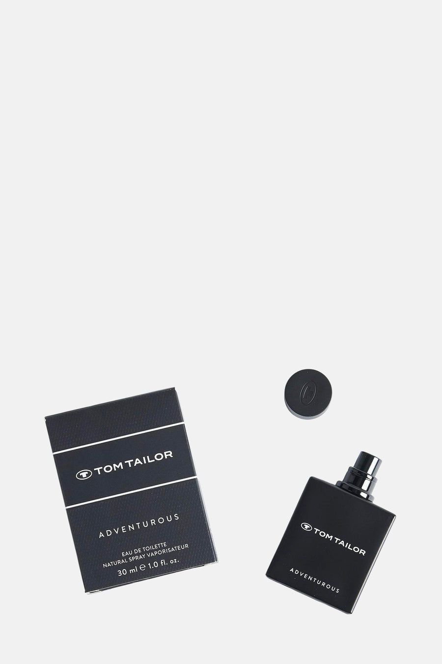 Flacon de parfum noir par Tom Tailor, avec la boîte, le vaporisateur et le bouchon à côté.
