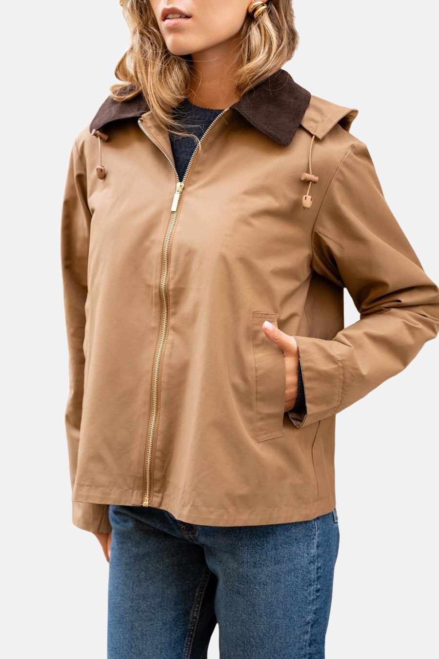 Imperméable cognac de LAURA JO avec col marron et fermeture éclair dorée, porté avec un jean.
