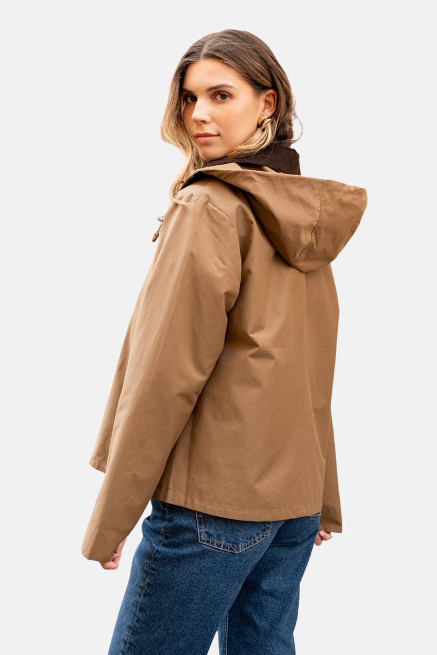 Imperméable couleur cognac de LAURA JO, avec capuche, porté avec un jean bleu.
