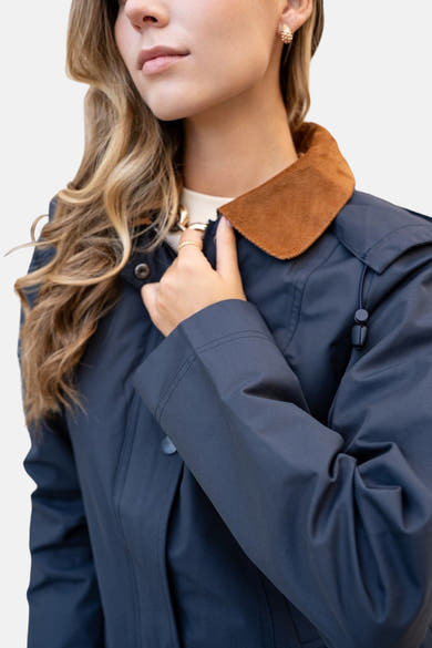 Blauwe regenjas van LAURA JO met bruine corduroy kraag en gouden sieraden.