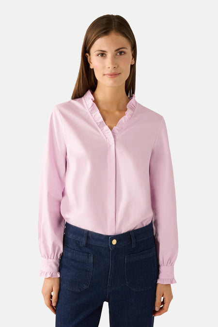 Blouse rose à manches longues de MORE & MORE, avec col à froufrous et pantalon en jean.
