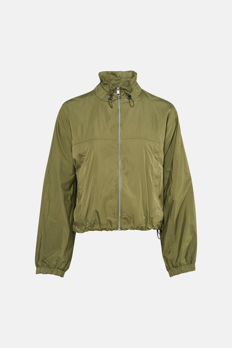 Korte groene jas van MORE & MORE, gedragen met een lichtblauwe jeans en sportschoenen.