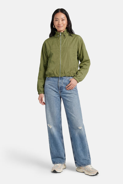 Veste courte verte de MORE & MORE, portée avec un jean bleu délavé et des chaussures de sport.