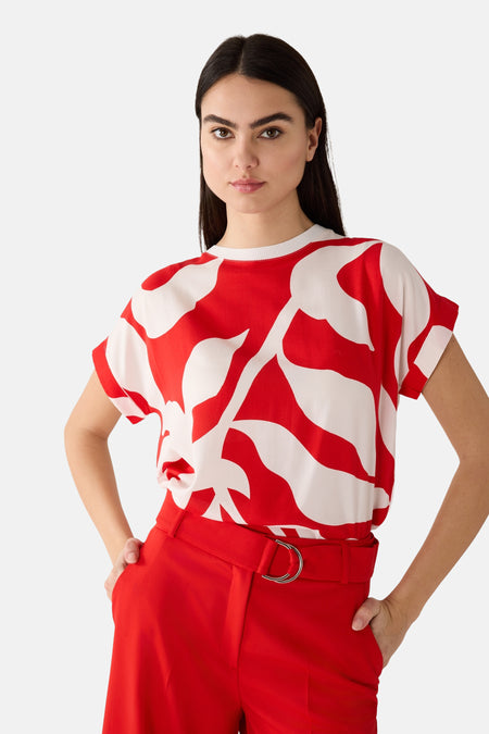 T-shirt à manches courtes multicolore de MORE & MORE avec imprimé abstrait rouge et blanc, porté avec un pantalon rouge.
