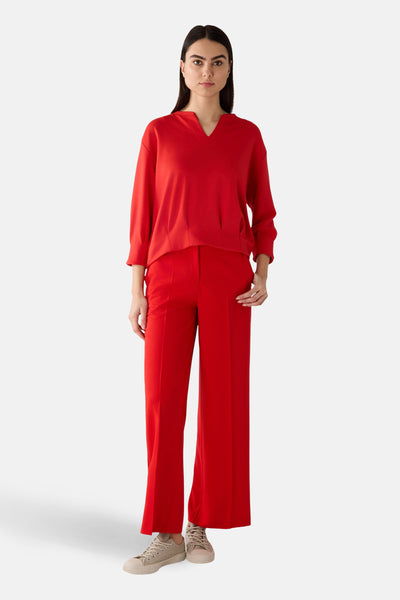 Sweat rouge de MORE & MORE, porté avec un pantalon rouge assorti et des chaussures beiges.