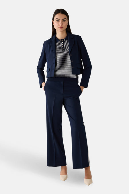 Polo multicolore de MORE & MORE à rayures horizontales, porté avec un blazer et un pantalon tailleur bleu marine.