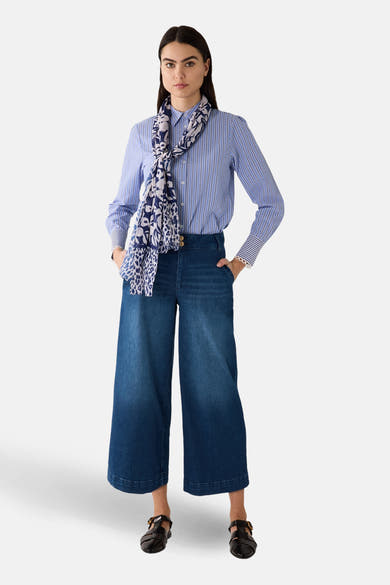 Chemisier bleu à rayures par MORE & MORE, porté avec un foulard imprimé et un pantalon large en denim.