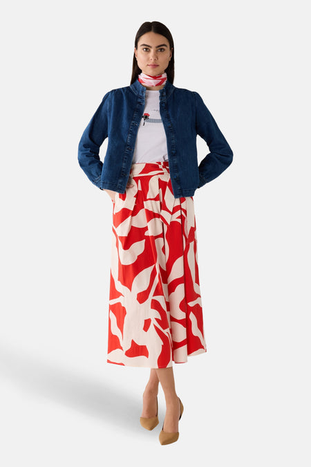 Jupe mi-longue multicolore de MORE & MORE, à motif floral rouge et beige, portée avec une veste en jean et des escarpins marron.